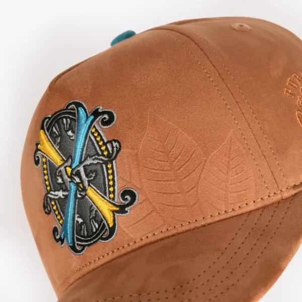 Opus X Society Snapback Hat Suede Earth Limited Edition 6 Close up of the Opus X Society crest patch and debossed tobacco leaves on tan suede