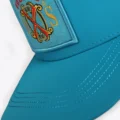 Close up of the Fuente OXS crest patch and stitched teal brim on the Opus X Society trucker hat