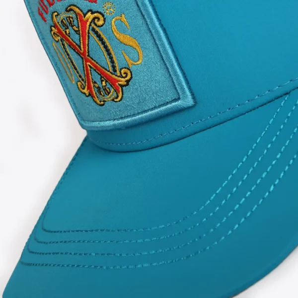Opus X Society Trucker Hat Teal and Yellow Limited Edition 5 Close up of the Fuente OXS crest patch and stitched teal brim on the Opus X Society trucker hat