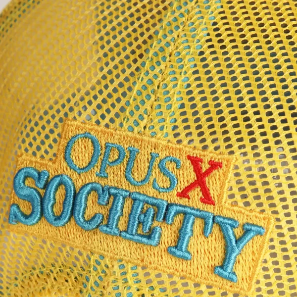 Opus X Society Trucker Hat Teal and Yellow Limited Edition 7 Close up of the Opus X Society embroidery with a red X on the yellow mesh back
